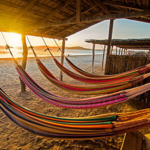 Hammocks on a beach at sunset.